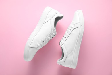 Photo of Pair of stylish white sneakers on pink background, top view