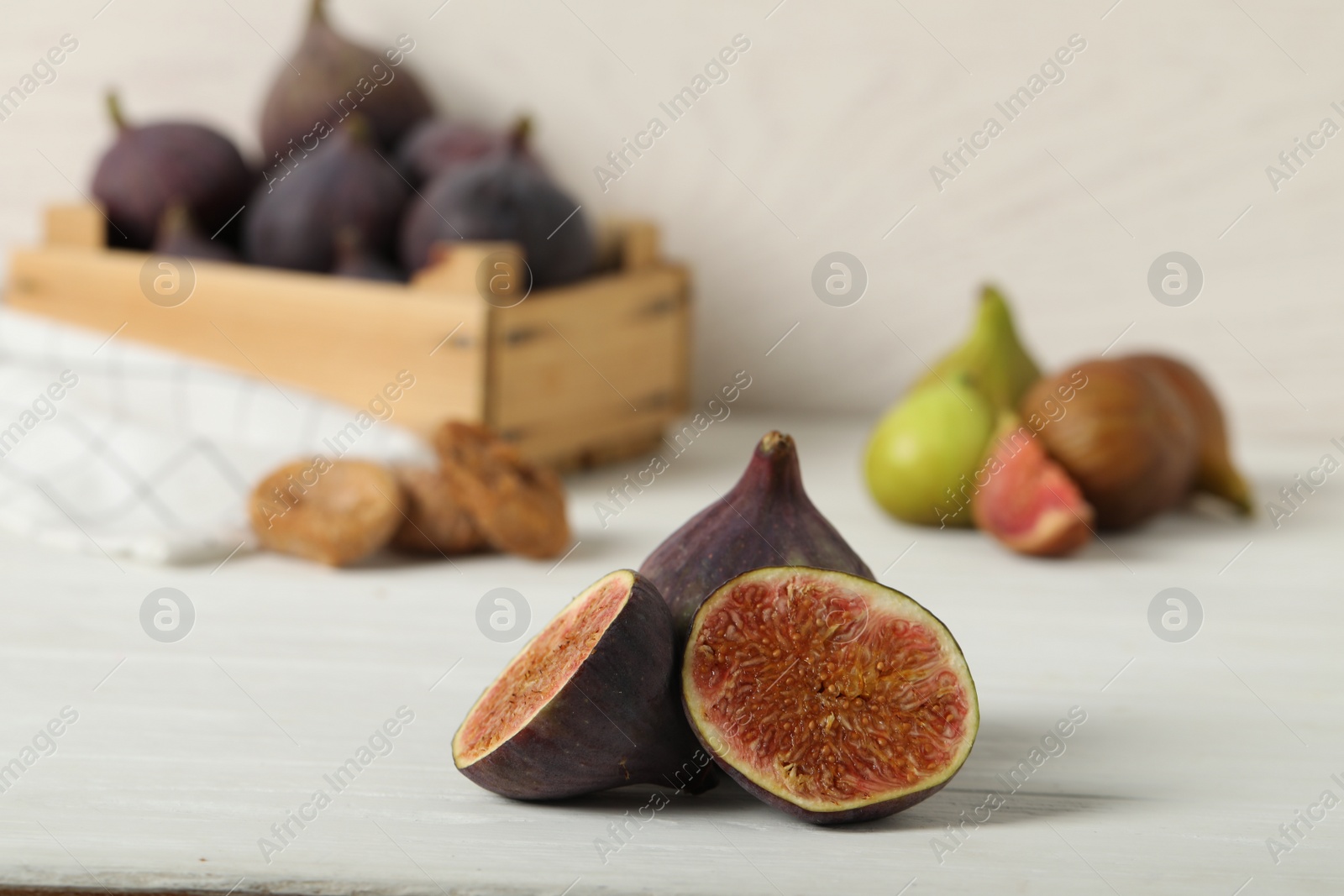 Photo of Tasty raw cut and whole figs on white table, closeup