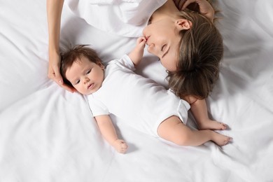 Photo of Mother and her little baby lying on bed, top view