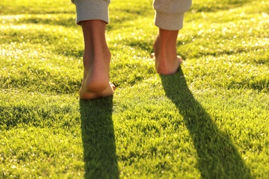 Man walking barefoot on fresh green grass, closeup