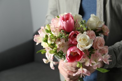 Photo of Man holding bouquet of beautiful flowers indoors, closeup