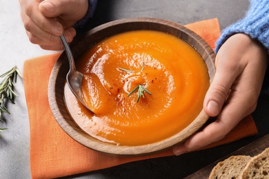 Photo of Woman eating tasty sweet potato soup at table, closeup