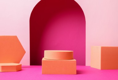 Photo of Many orange geometric figures on pink background. Stylish presentation for product