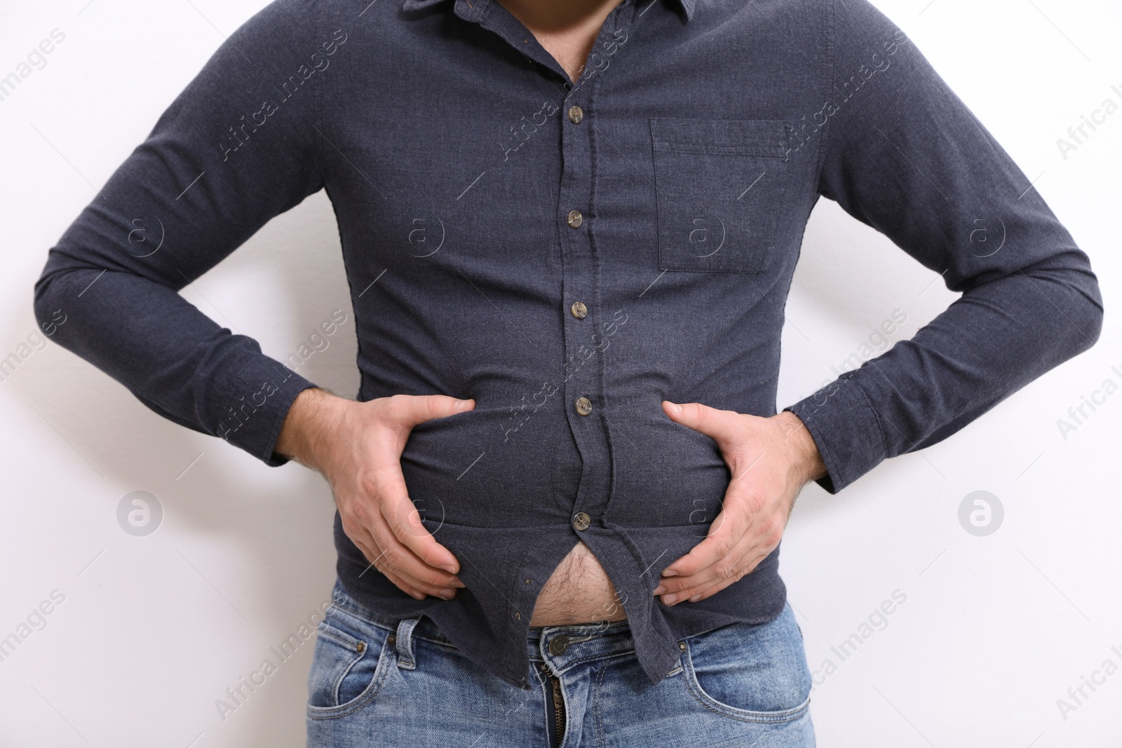 Photo of Man wearing tight shirt on white background, closeup. Overweight problem