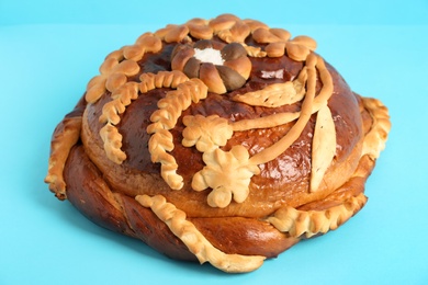 Photo of Fresh korovai on light blue background, closeup. Ukrainian bread and salt welcoming tradition