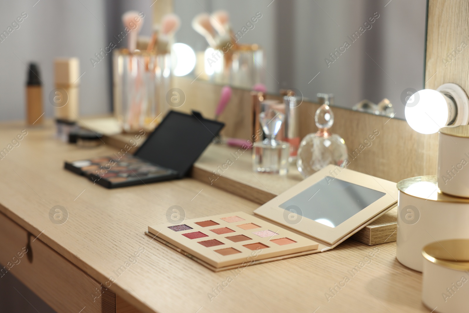 Photo of Cosmetic products on wooden dressing table in makeup room