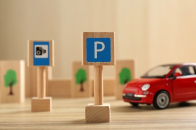 Photo of Traffic sign Parking lot and toy car on wooden table. Passing driving license exam