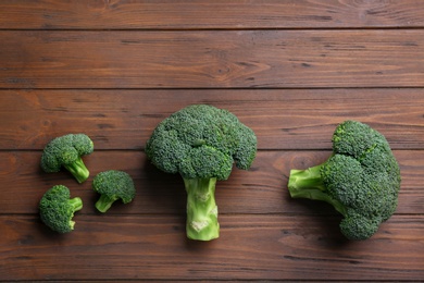 Photo of Flat lay composition of fresh green broccoli on wooden table, space for text