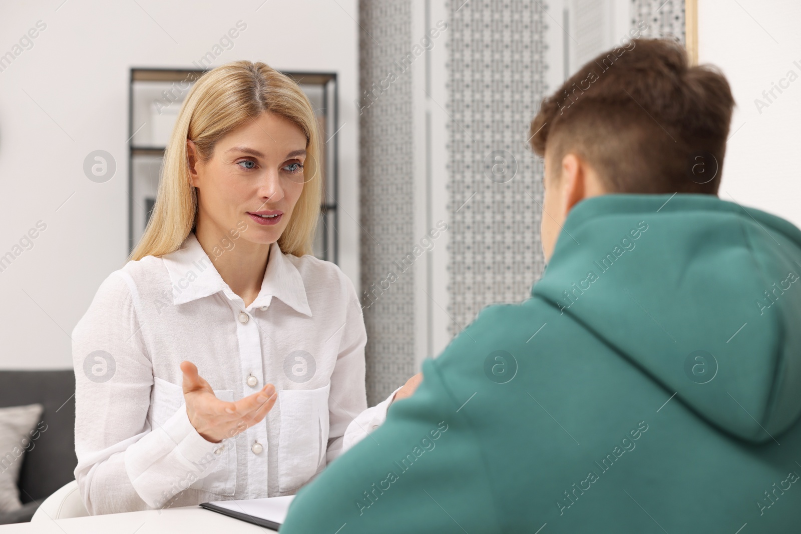 Photo of Psychologist working with teenage boy at table in office