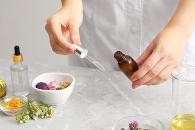 Photo of Scientist developing cosmetic oil at light grey table, closeup