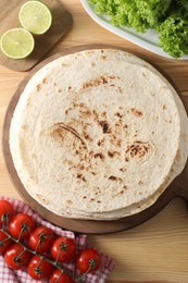 Many tasty homemade tortillas and products on wooden table, flat lay