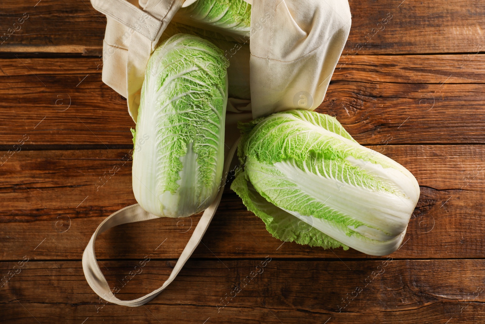 Photo of Fresh ripe Chinese cabbages and textile eco bag on wooden table, flat lay