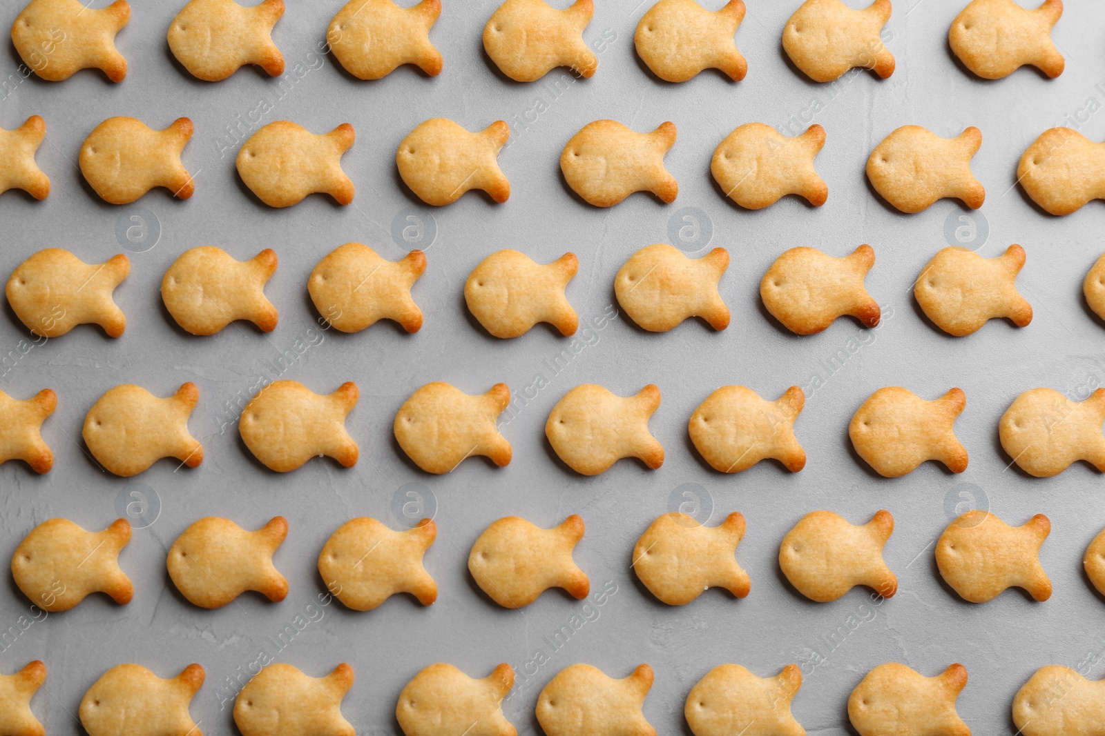 Photo of Delicious goldfish crackers on grey table, flat lay