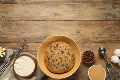Photo of Bowl with dough and ingredients for cooking chocolate chip cookies on wooden table, flat lay. Space for text