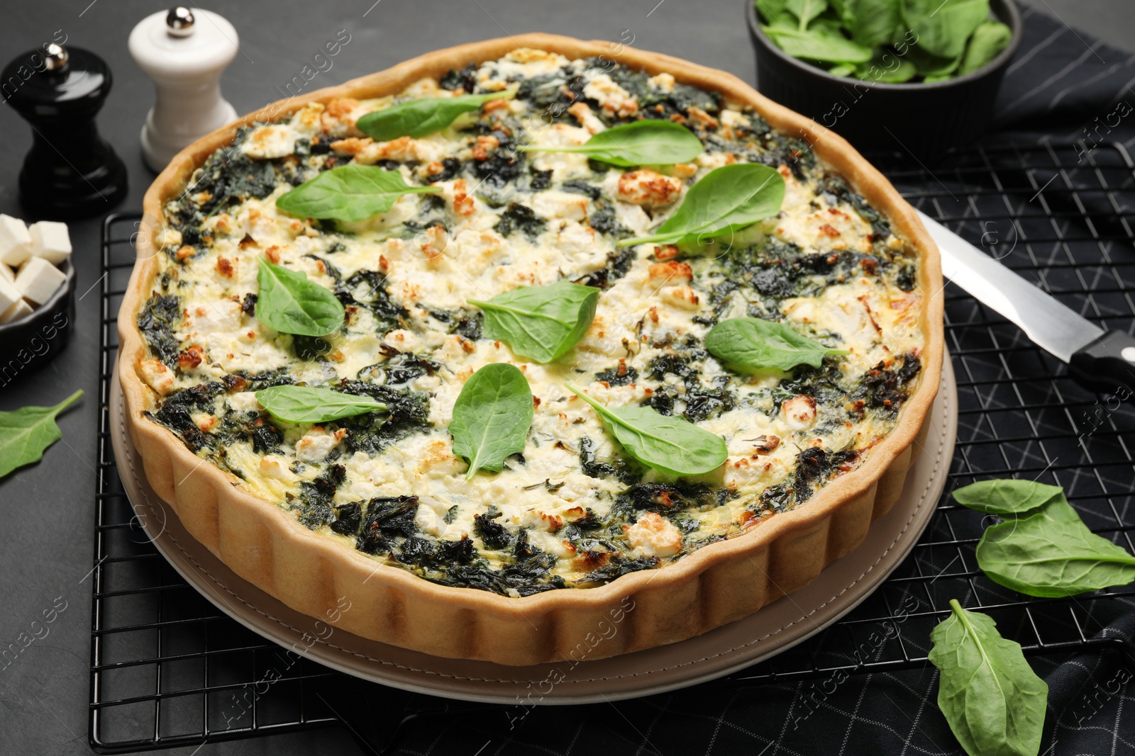Photo of Delicious homemade spinach quiche on black table, closeup
