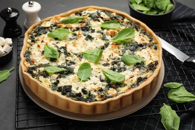 Delicious homemade spinach quiche on black table, closeup