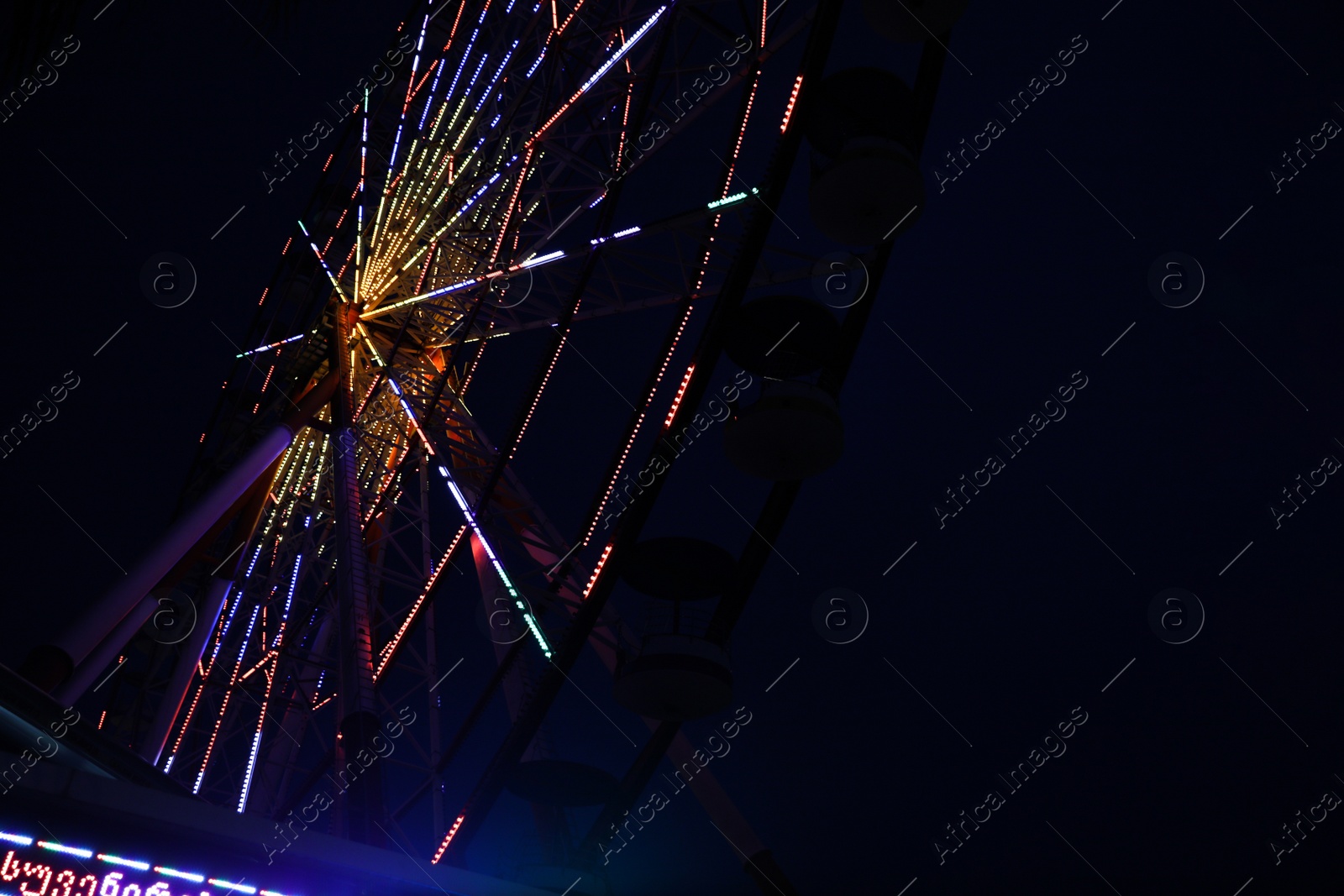 Photo of Beautiful glowing Ferris wheel against dark sky, low angle view