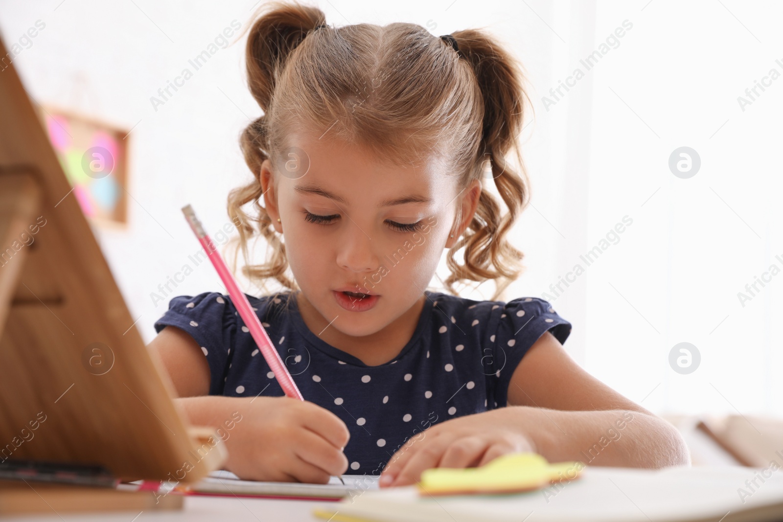 Photo of Cute little girl doing homework at table