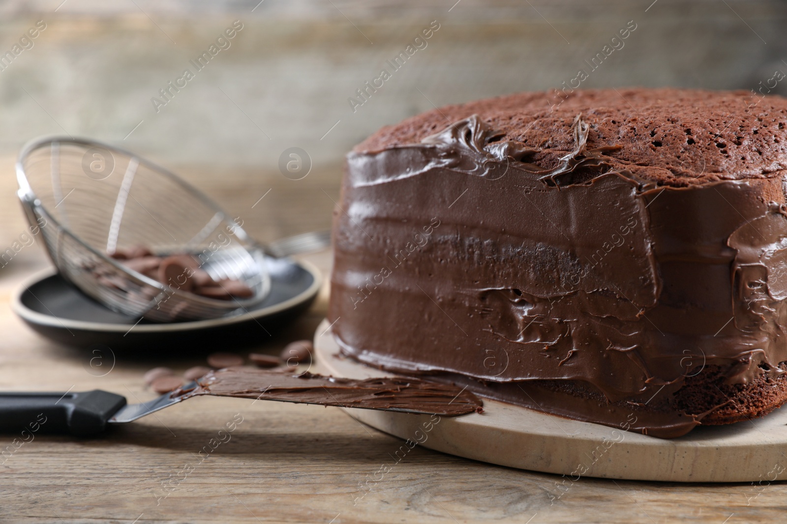 Photo of Delicious homemade layer cake with chocolate cream on wooden table, closeup