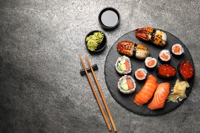 Photo of Set of delicious sushi rolls on dark grey table, flat lay