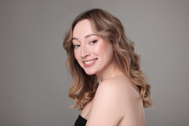 Photo of Portrait of smiling woman with curly hair on grey background