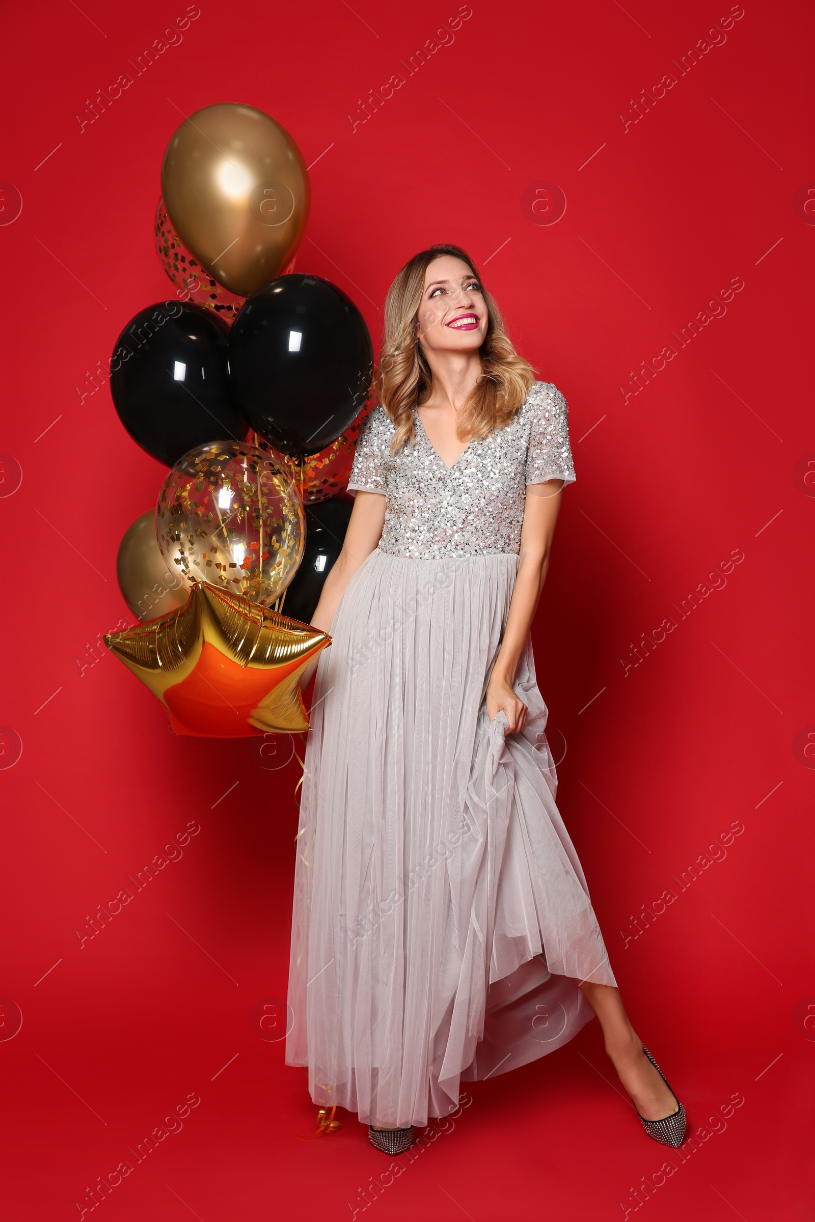 Photo of Happy woman with air balloons on red background. Christmas party