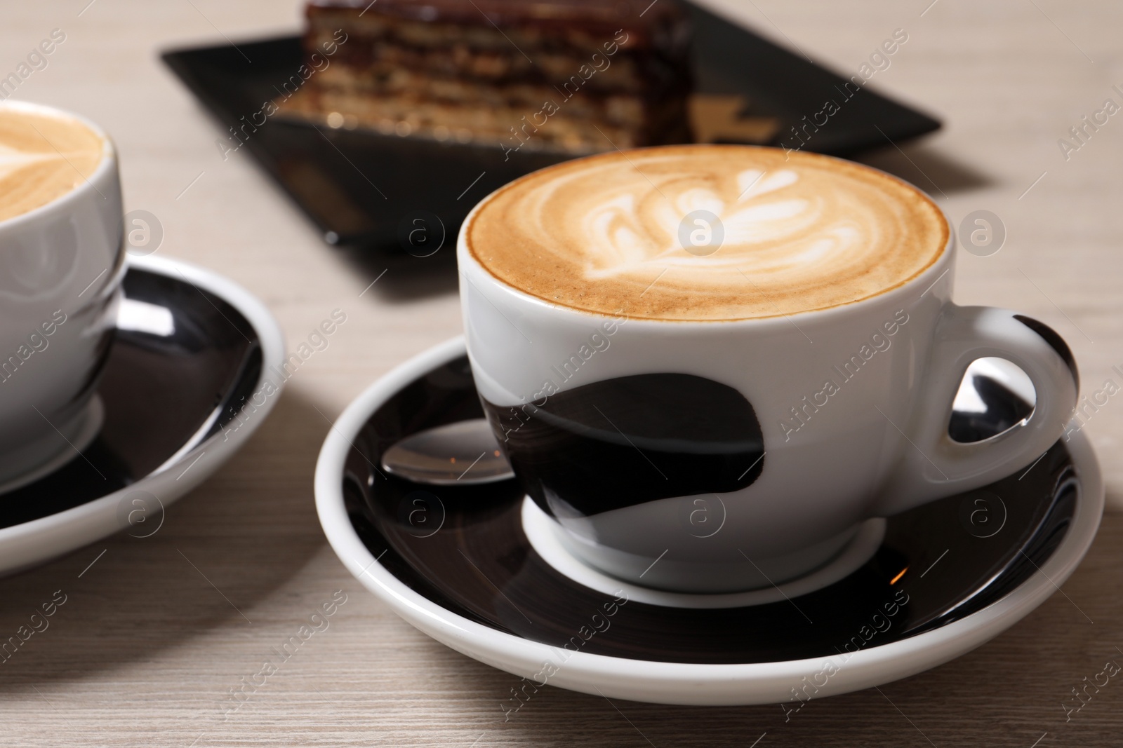 Photo of Cups of aromatic coffee on wooden table, closeup