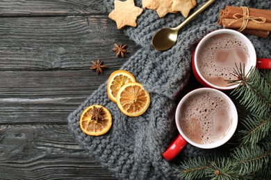 Flat lay composition with cups of tasty cocoa on black wooden table