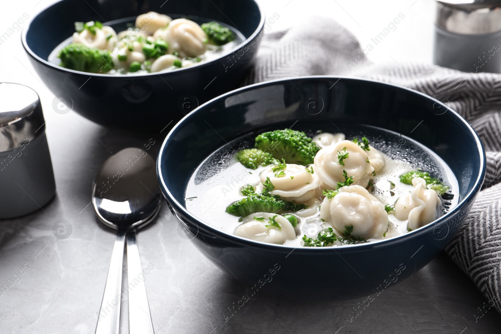 Photo of Tasty dumplings in broth served on grey table