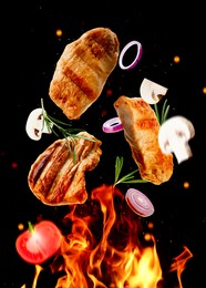 Image of Tasty grilled meat, different vegetables and fire flame on dark background