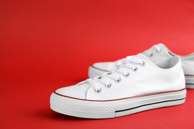 Photo of Pair of stylish sneakers on red background, closeup