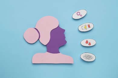 Photo of Woman's health. Female paper figure and different stickers on light blue background, flat lay