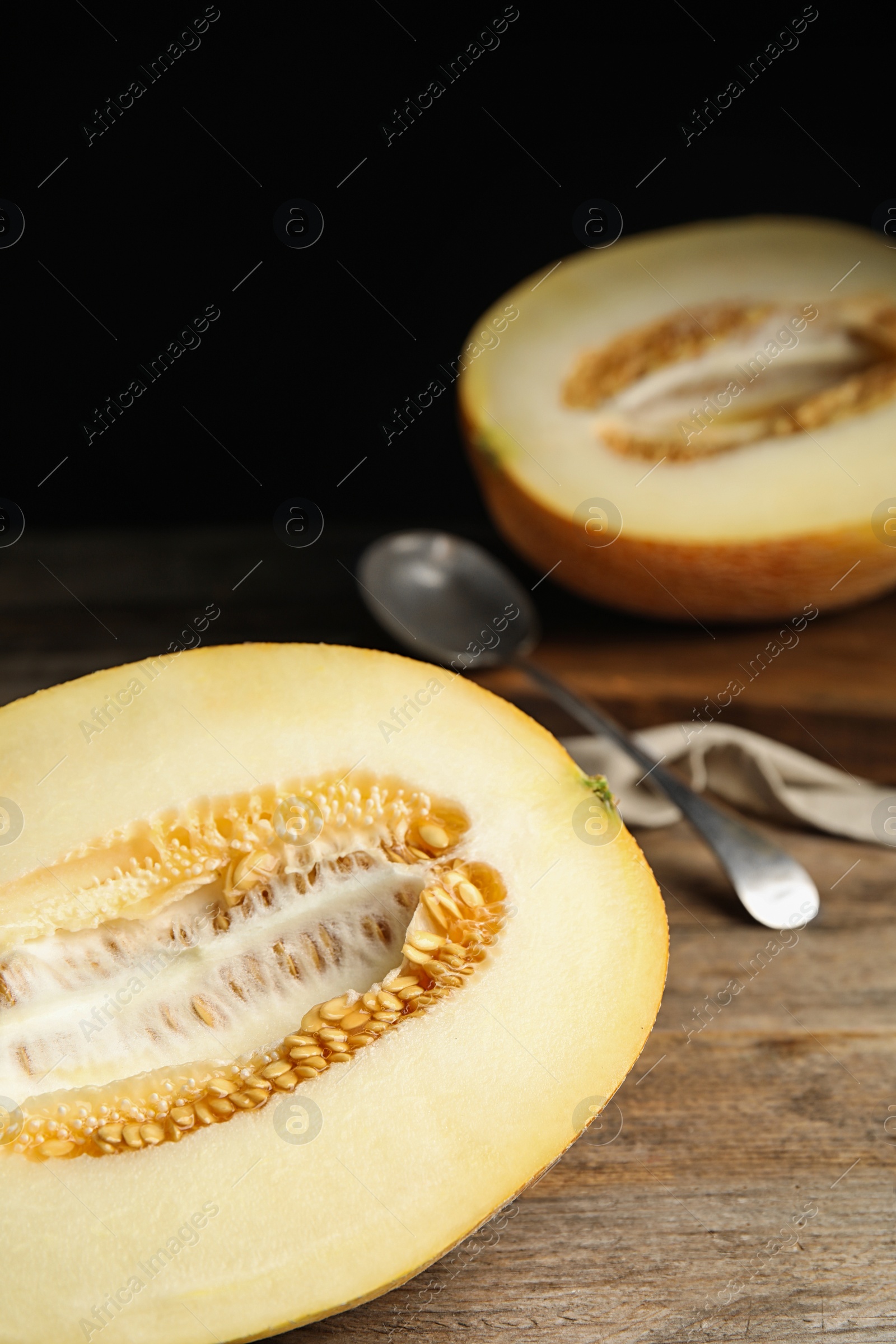 Photo of Half of tasty ripe melon on wooden table, closeup