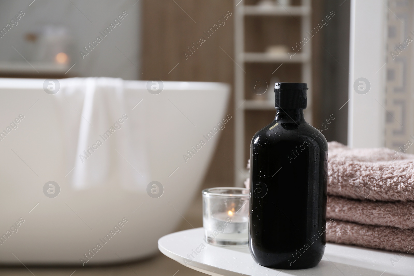 Photo of Bottle of shower gel and fresh towels on white table in bathroom. Space for text