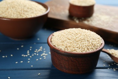 Photo of Sesame seeds in bowls on blue wooden table