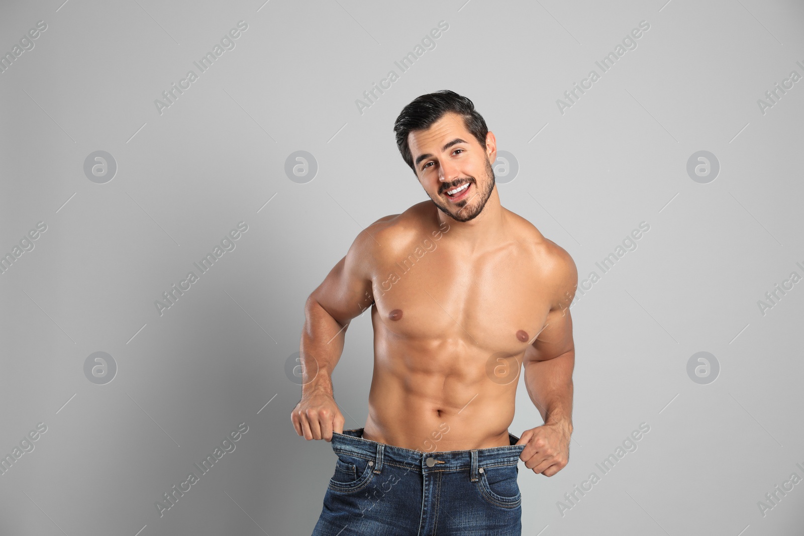 Photo of Young man with slim body in old big size jeans on grey background