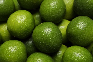 Fresh ripe limes with water drops as background, closeup