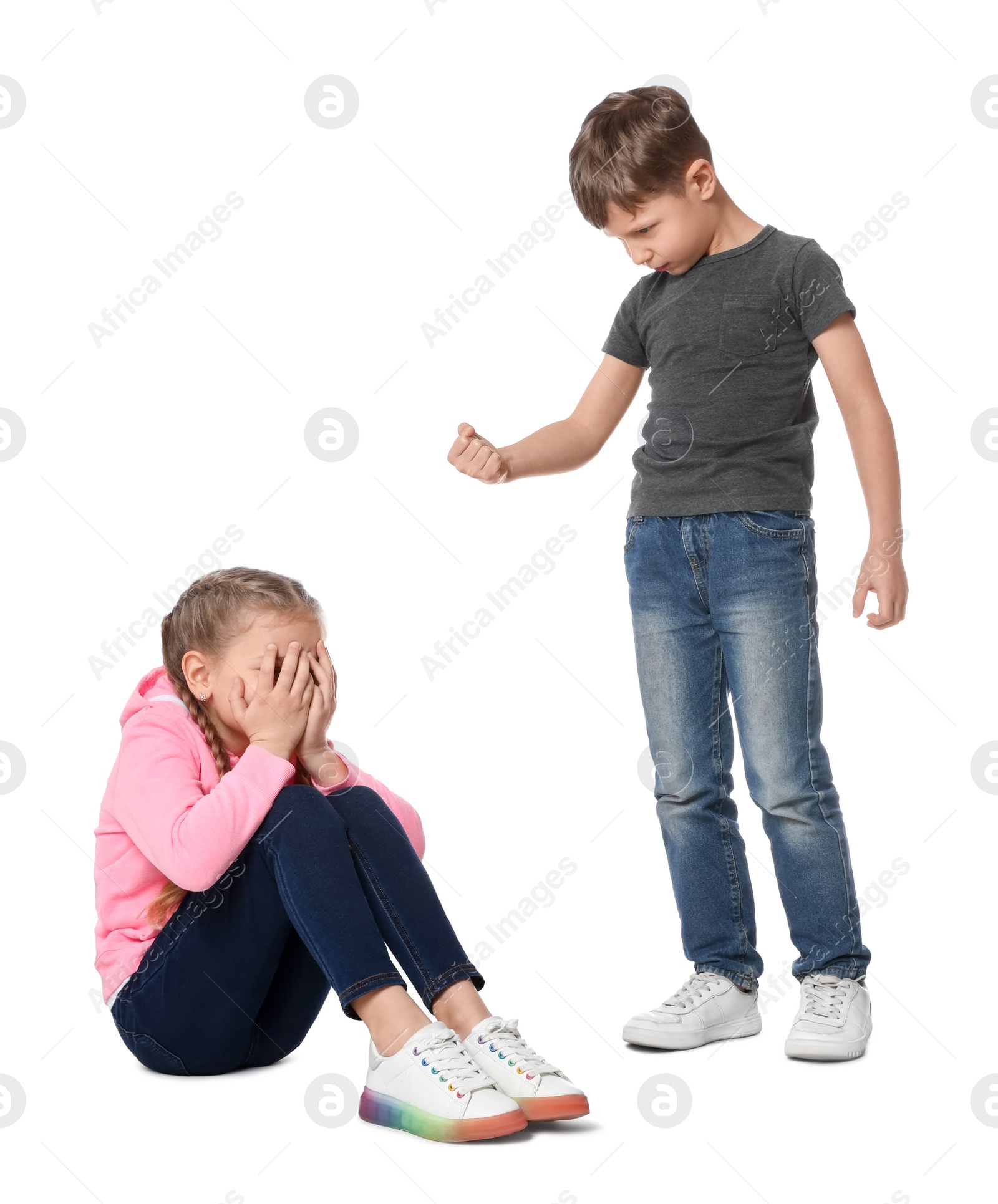 Photo of Boy with clenched fist looking at scared girl on white background. Children's bullying