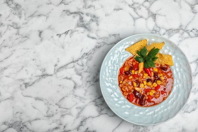 Plate with tasty chili con carne on marble background, top view. Space for text