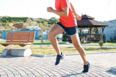 Sporty man running outdoors on sunny morning