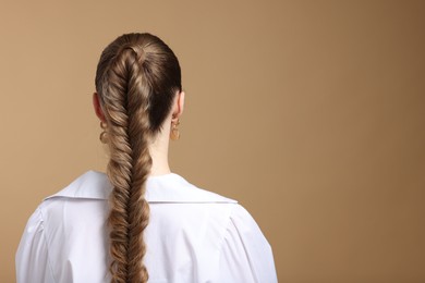 Photo of Woman with braided hair on brown background, back view. Space for text