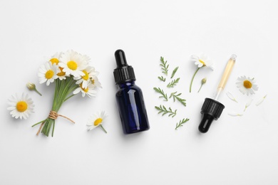 Photo of Composition with chamomile flowers and cosmetic bottle of essential oil on white background, top view