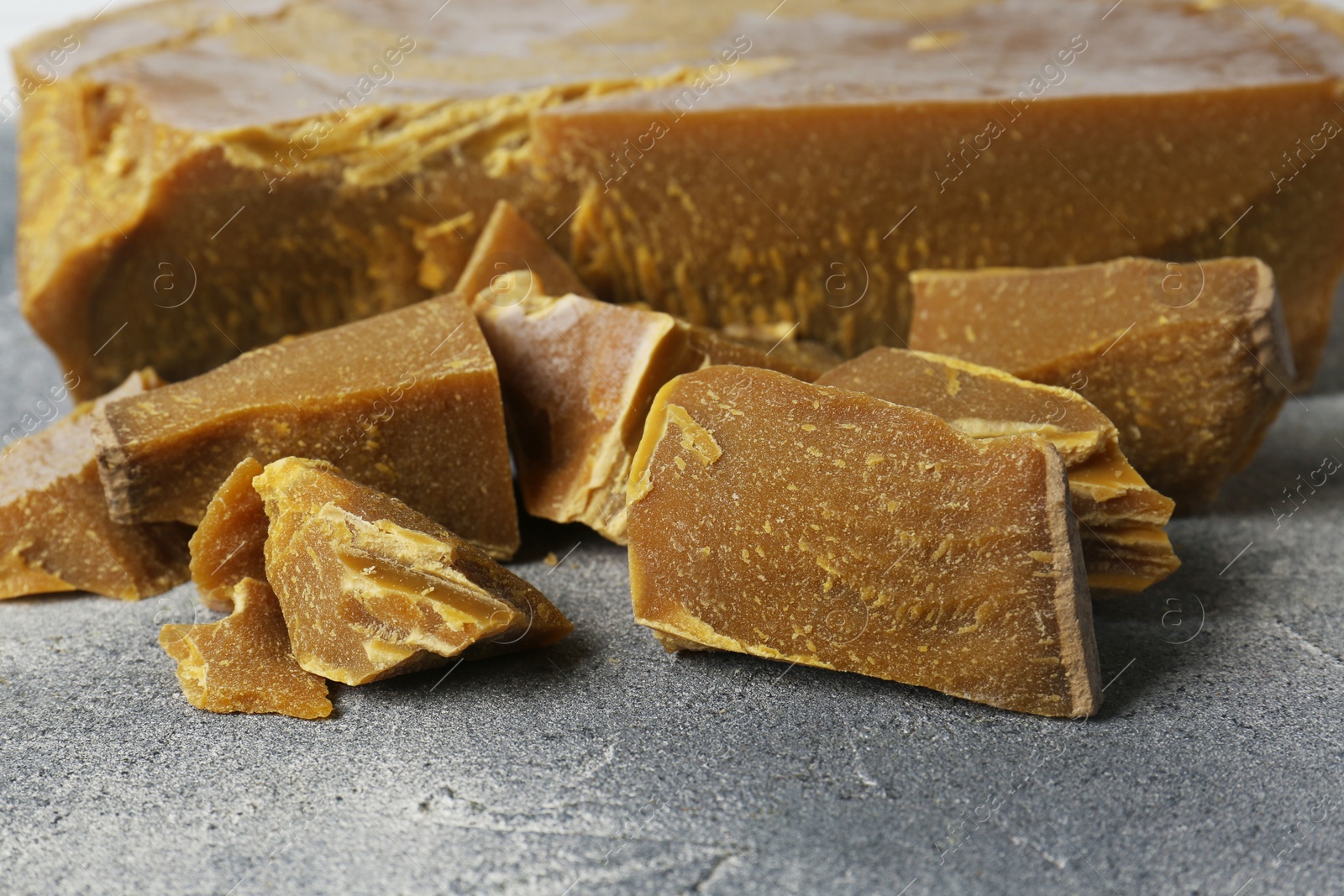 Photo of Natural organic beeswax blocks on light grey table, closeup