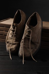 Photo of Poverty. Pair of old shoes on black wooden table