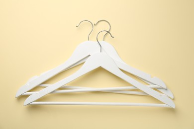 Photo of White hangers on pale yellow background, top view