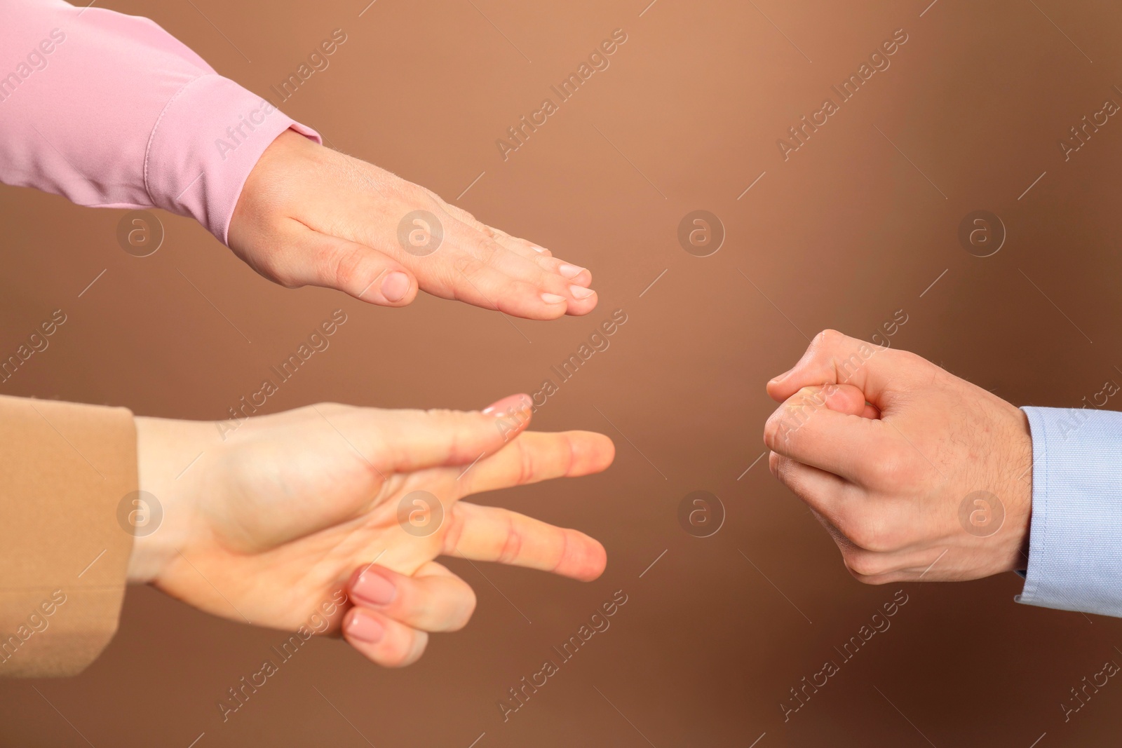 Photo of People playing rock, paper and scissors on brown background, closeup