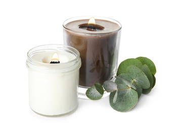 Photo of Aromatic candles with wooden wicks and eucalyptus branch on white background