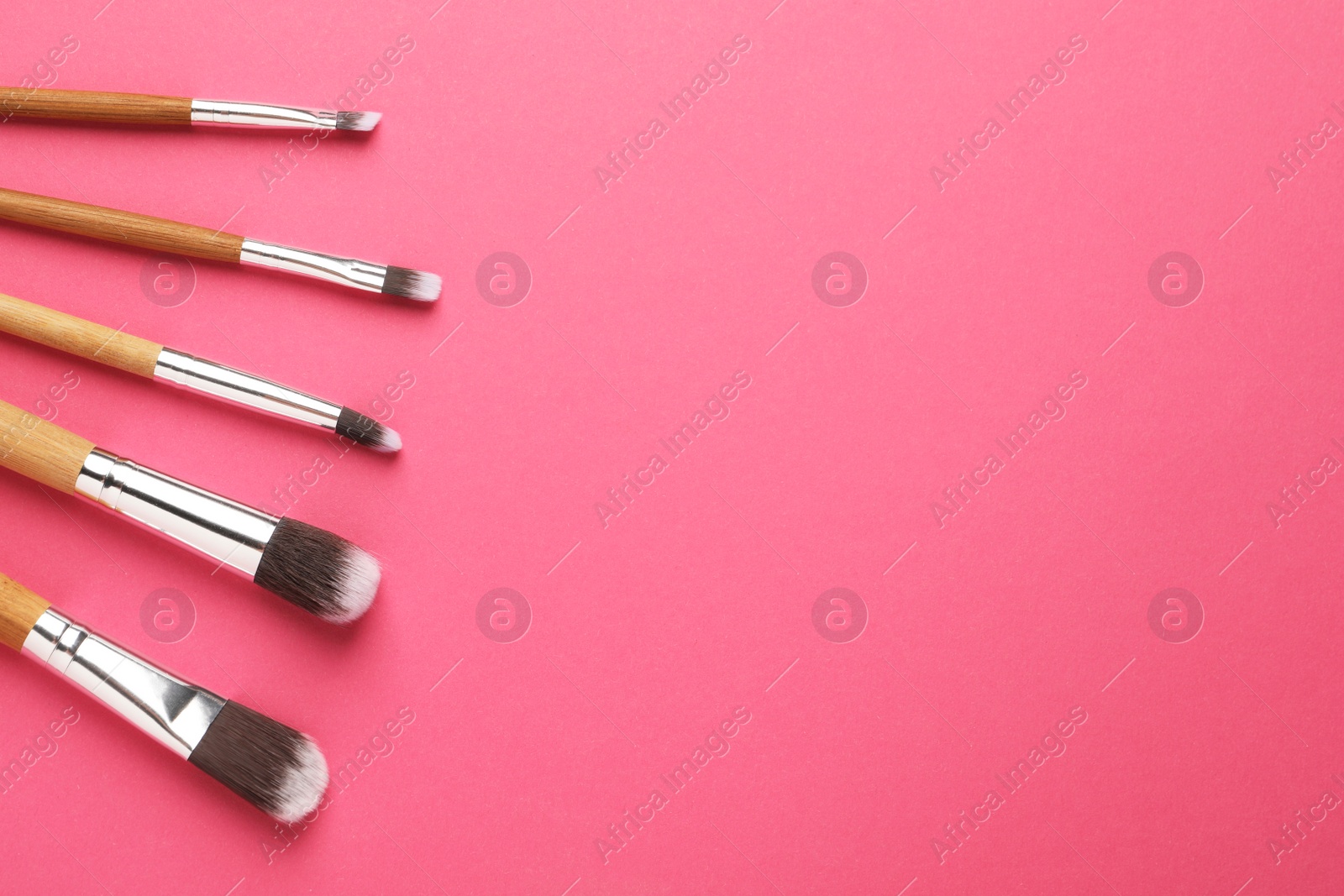 Photo of Set of makeup brushes on pink background, flat lay. Space for text