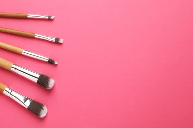 Photo of Set of makeup brushes on pink background, flat lay. Space for text