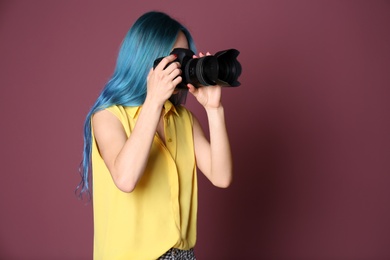 Photo of Young female photographer with camera on color background